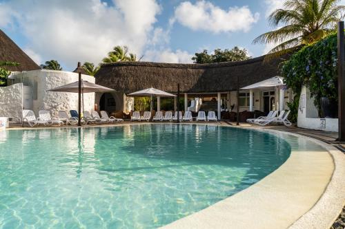 a large swimming pool with chairs and umbrellas at Casuarina Resort and Spa in Trou aux Biches