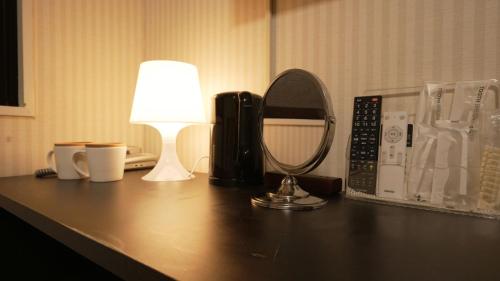 a desk with a lamp and a mirror on it at HOTEL THE GARDEN Ⅵ ICHINOMIYA in Ichinomiya