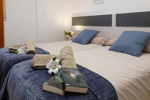 a bedroom with two beds with a book and flowers at APARTAMETO BAZTANGOA I Centro Elizondo in Elizondo