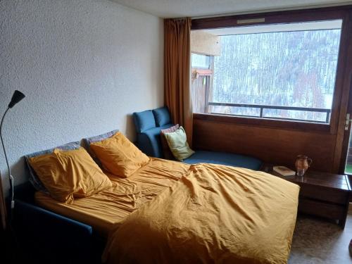 a bedroom with a bed and a chair and a window at Studio Le Fontagnel in Molines-en-Queyras