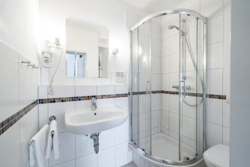 a white bathroom with a sink and a shower at Gutshaus Barkow in Barkhagen