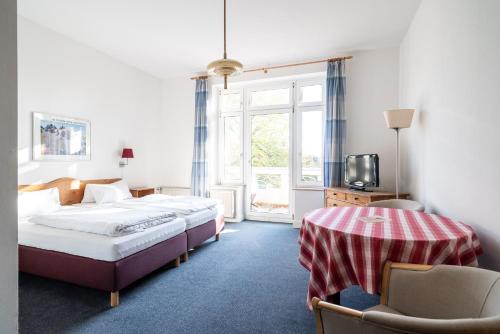 a bedroom with two beds and a table and a tv at Gutshaus Barkow in Barkhagen