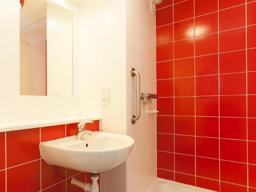 a bathroom with a sink and a mirror and red tiles at Travelodge Middlesbrough in Middlesbrough