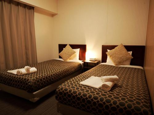 two beds in a hotel room with towels on them at HOTEL THE GARDEN Ⅵ ICHINOMIYA in Ichinomiya