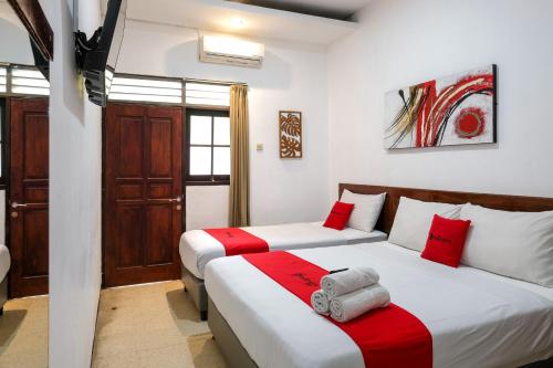 two beds in a room with red and white at RedDoorz @ Soekarno Hatta 2 in Malang