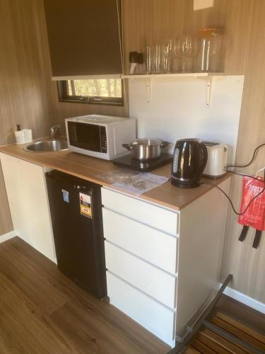 a small kitchen with a microwave and a sink at Plain Bush by Tiny Away in Bohena Creek