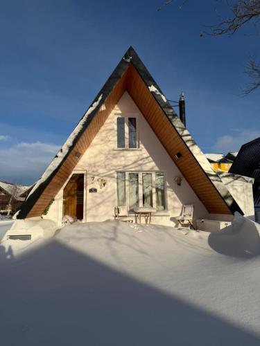 a house in the snow with a table and chairs at Chalé Zimbro, Serra da Estrela, Penhas da Saúde in Penhas da Saúde