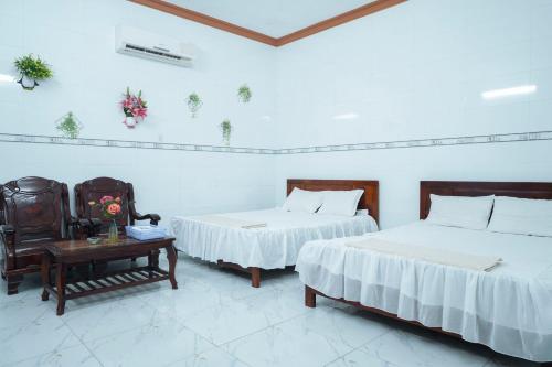 a bedroom with two beds and a table with a chair at Nhà Nghỉ Hiếu Thuận in Nhơn Trạch