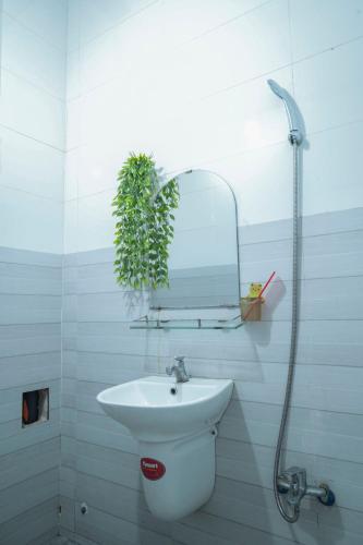 a bathroom with a sink and a mirror and a plant at Nhà Nghỉ Hiếu Thuận in Nhơn Trạch