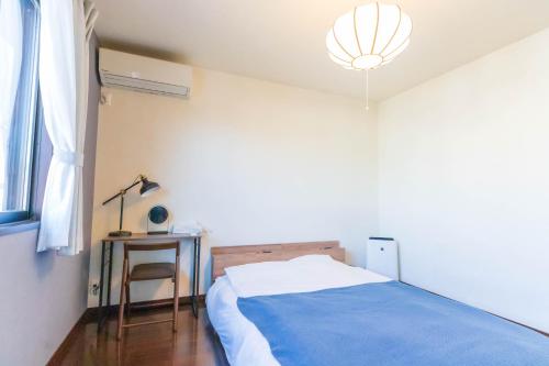 a bedroom with a bed and a table and a lamp at Fuji Life House in Fuji