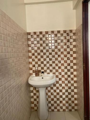 a bathroom with a white sink and a checkered wall at Bliss Residence Studio Mtwapa in Mtwapa