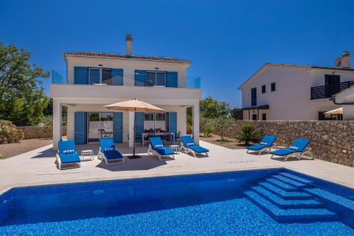 a villa with a swimming pool with chairs and an umbrella at Holiday house DAN with private pool in Kras