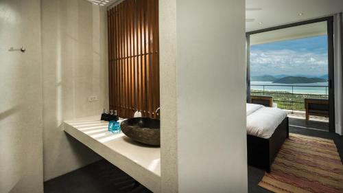 a bathroom with a sink and a bedroom with a view at Kasalong in Laem Set Beach