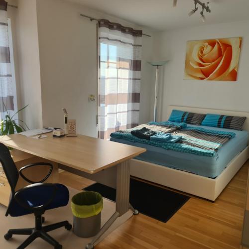 a bedroom with a bed and a desk and a table at Apartment „Am Südhang“ in Adelzhausen