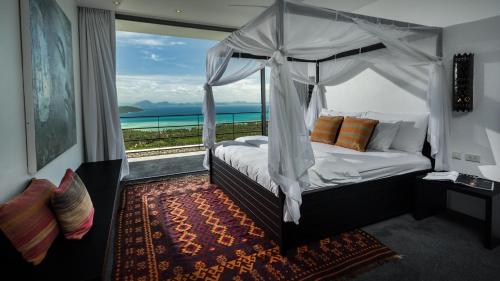 a bedroom with a canopy bed with a view of the ocean at Kasalong in Laem Set Beach