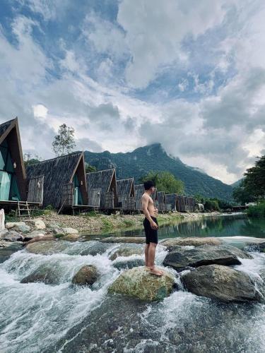 a man standing on some rocks in a river at Vangvieng Angsavanh Resort in Vang Vieng