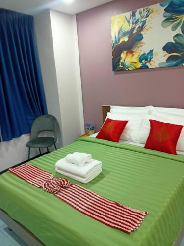 a bedroom with a large green bed with red pillows at 9 Home Phuket in Ban Rangeng