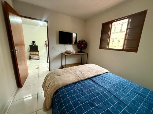 a bedroom with a bed with a blue blanket and a window at Kitnet Econômica e Funcional in Campo Grande