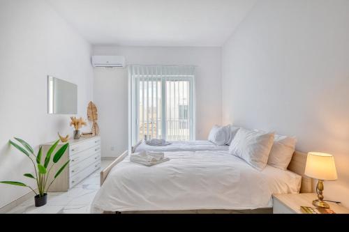 a white bedroom with a bed and a window at New Family-Friendly & Spacious Apartment by SF Homes in Fgura
