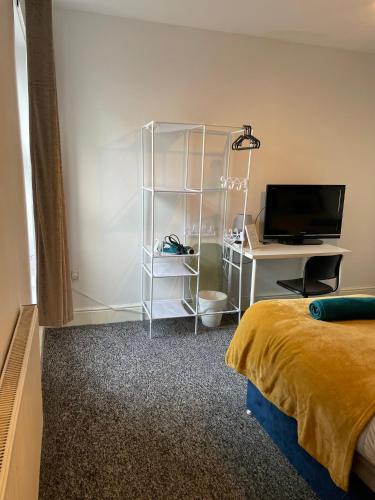a bedroom with a bed and a desk with a television at IVY GREEN HOUSE - STYLISH VALUE STAY, SLEEPS upto 7, LUXURY BEDS, CENTRAL, WIFI, NETFLIX, FREE PARKING in Derby