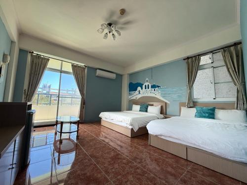una camera d'albergo con due letti e un balcone di Camellia B&B a Città di Taitung