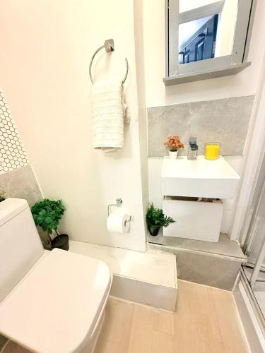 a white bathroom with a toilet and a sink at 10 Minutes to Central London Vaux in London
