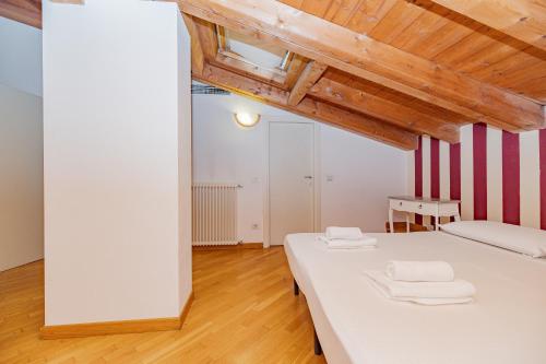 a bedroom with a white bed and a wooden ceiling at Mansarda in Piazza Duomo in Milan