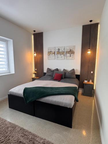 a bedroom with a large bed with a green blanket at CFS Apartman in Debrecen