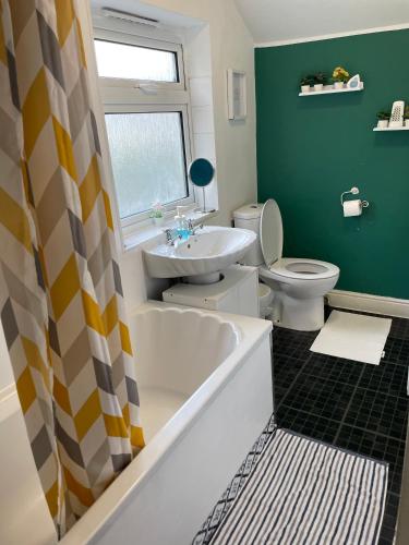 a bathroom with a tub and a toilet and a sink at IVY GREEN HOUSE - STYLISH VALUE STAY, SLEEPS upto 7, LUXURY BEDS, CENTRAL, WIFI, NETFLIX, FREE PARKING in Derby