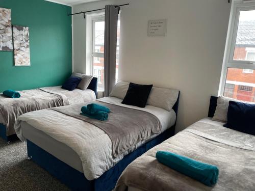 a room with two beds and a couch at IVY GREEN HOUSE - STYLISH VALUE STAY, SLEEPS upto 7, LUXURY BEDS, CENTRAL, WIFI, NETFLIX, FREE PARKING in Derby