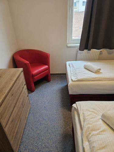 a room with a red chair and two beds at Hotel Astral Vienna in Vienna