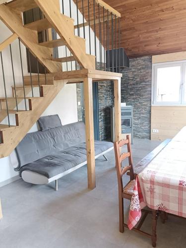 a living room with a couch and a staircase at Le Chalet des Pas Sages in Longevilles-Mont-dʼOr