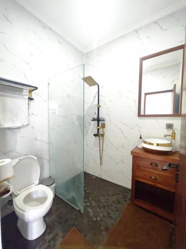 a bathroom with a toilet and a glass shower at Santo Guesthouse in Canggu