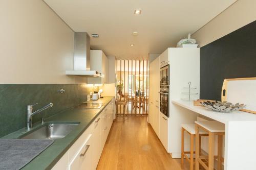 a kitchen with white cabinets and green walls at Villa Mar in Troia