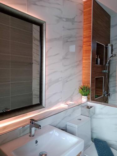 a bathroom with a sink and a mirror and a toilet at Niramit Pool Villa in Ban Chong Phli