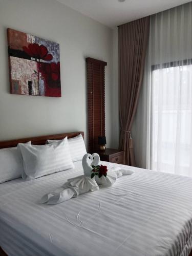 a bedroom with a white bed with a stuffed animal on it at Niramit Pool Villa in Ban Chong Phli