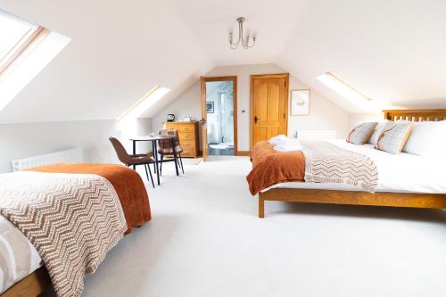 a attic bedroom with two beds and a table at Edenmore Cottage Bed & Breakfast in Moorefield