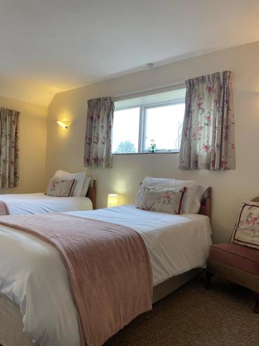 a bedroom with two beds and a window at The Barn Guest House and Tearoom in Hutton le Hole