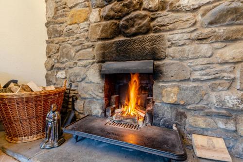 a stone fireplace with a fire in it at The Barn Guest House and Tearoom in Hutton le Hole
