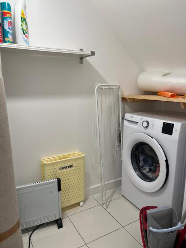 a laundry room with a washing machine and a shelf at Modern 3 Bedroom House in Hornchurch in Hornchurch