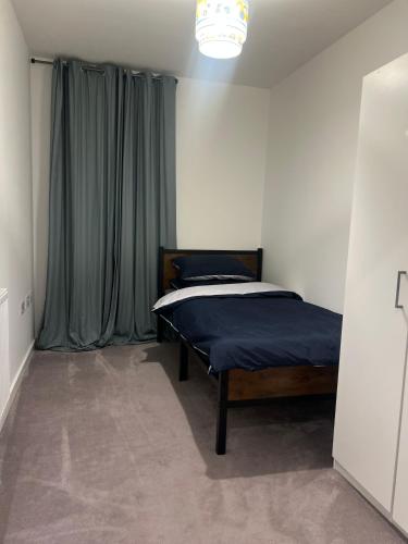 a bedroom with a bed with blue sheets and a window at Modern 3 Bedroom House in Hornchurch in Hornchurch