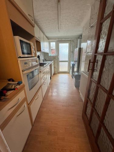 a kitchen with white appliances and a wooden floor at Hawkins Guesthouse in Milton