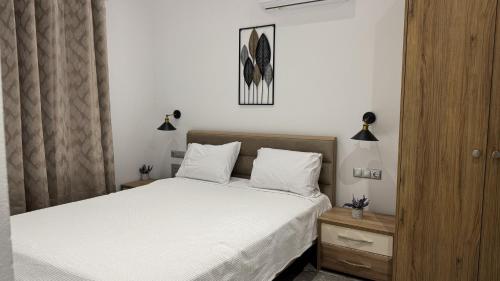 a bedroom with a bed with white sheets and white pillows at Διαμέρισμα με θέα - Sunset House Lemnos in Agios Ioannis Kaspaka