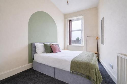 a bedroom with a large bed and a window at Group Stay 4BR Sleeps 11 Spacious with Parking in Glasgow