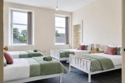 a bedroom with three beds and two windows at Group Stay 4BR Sleeps 11 Spacious with Parking in Glasgow