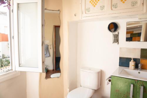 a bathroom with a toilet and a sink and a window at High Flyers Kite House in Tarifa