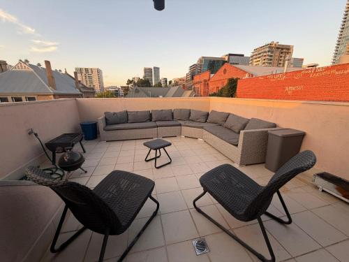 a patio with a couch and chairs on a rooftop at In the heart of Adelaide in Adelaide