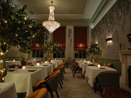 a restaurant with white tables and chairs and a chandelier at Seaham Hall and Serenity Spa in Seaham