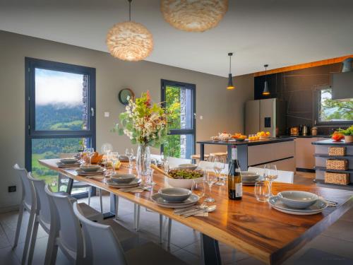 a kitchen with a long wooden table with plates and wine glasses at Chalet Confidentiel - OVO Network in Doucy