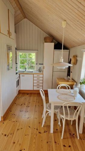 a kitchen with a white table and chairs in a room at Lilla huset in Klädesholmen
